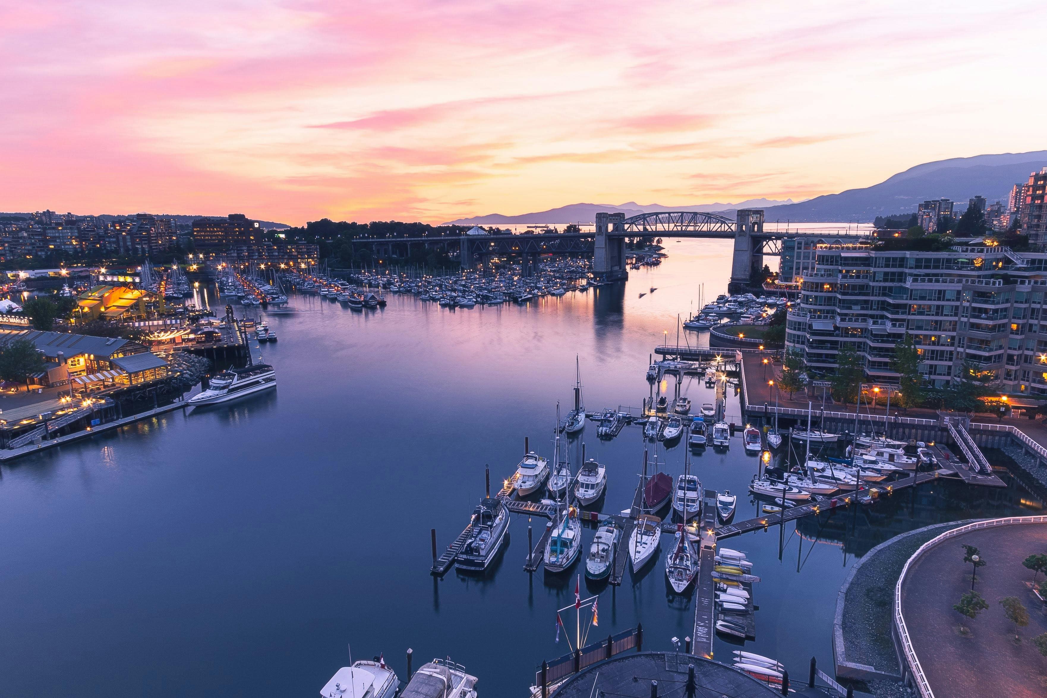 False Creek at sunset — boats moored along the marina, the Burrard Street Bridge crossing the water, and the North Shore mountains beyond