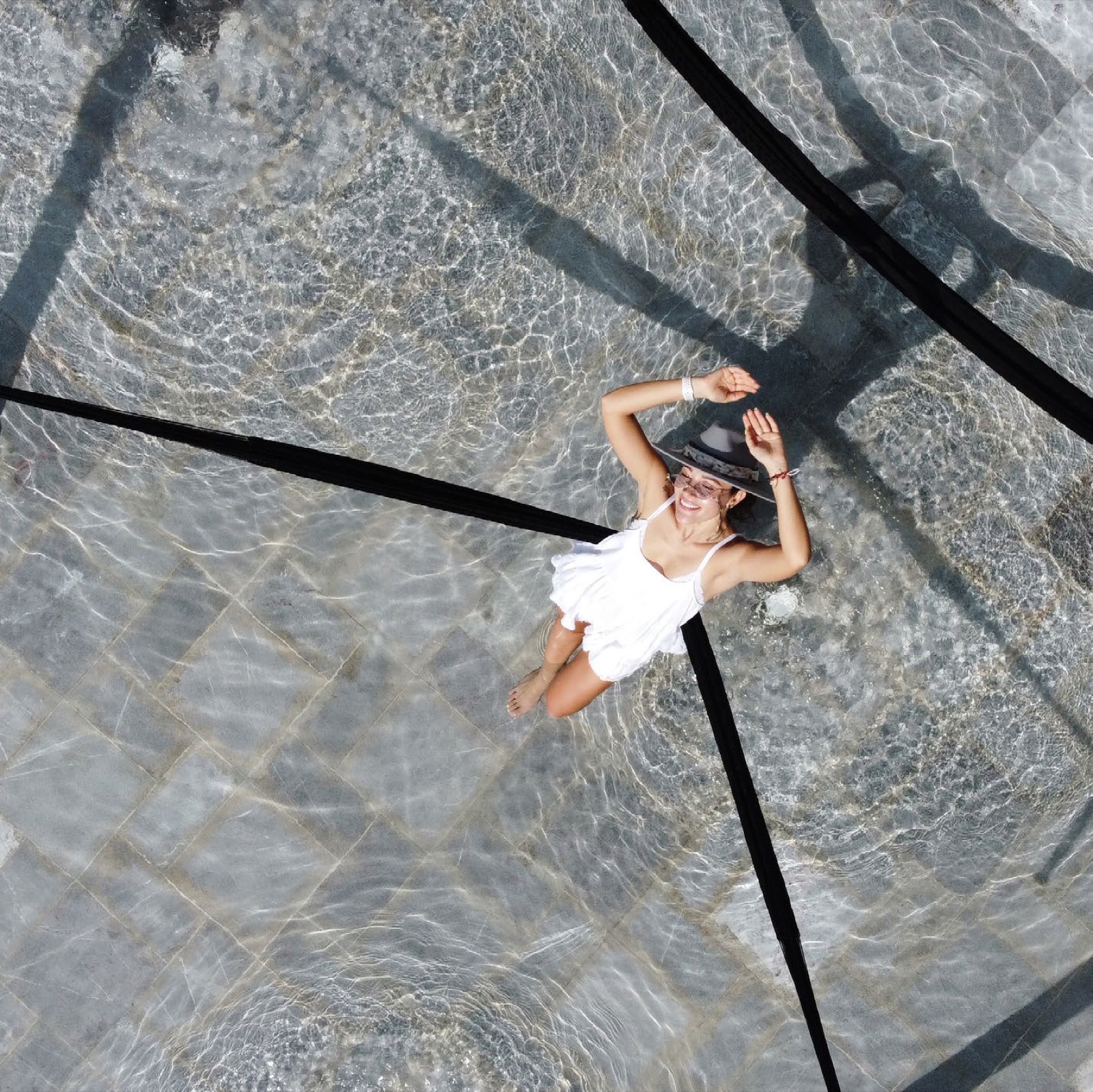 Overhead shot of a swimmer on the pool's stone tiles — lifestyle mood (1427x1426 — brochure p15)