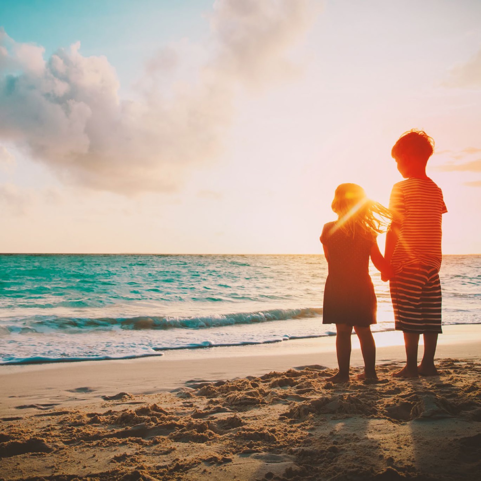 Children at the shoreline at golden hour — beach-lifestyle mood image (stock-style photo, 1369x1369 — brochure p3)